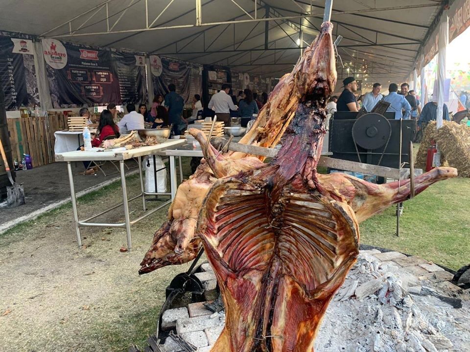 Lechón entero asándose lentamente en espetón giratorio