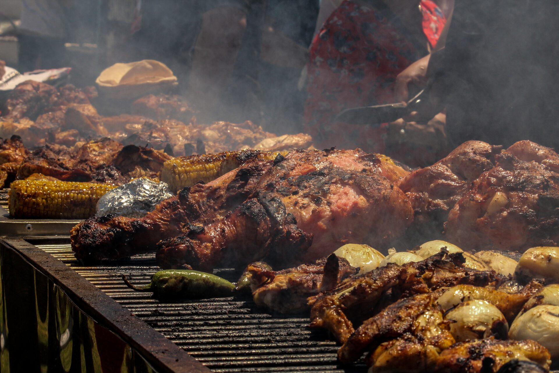 Parrilla con elotes y cortes de carne sobre las brasas