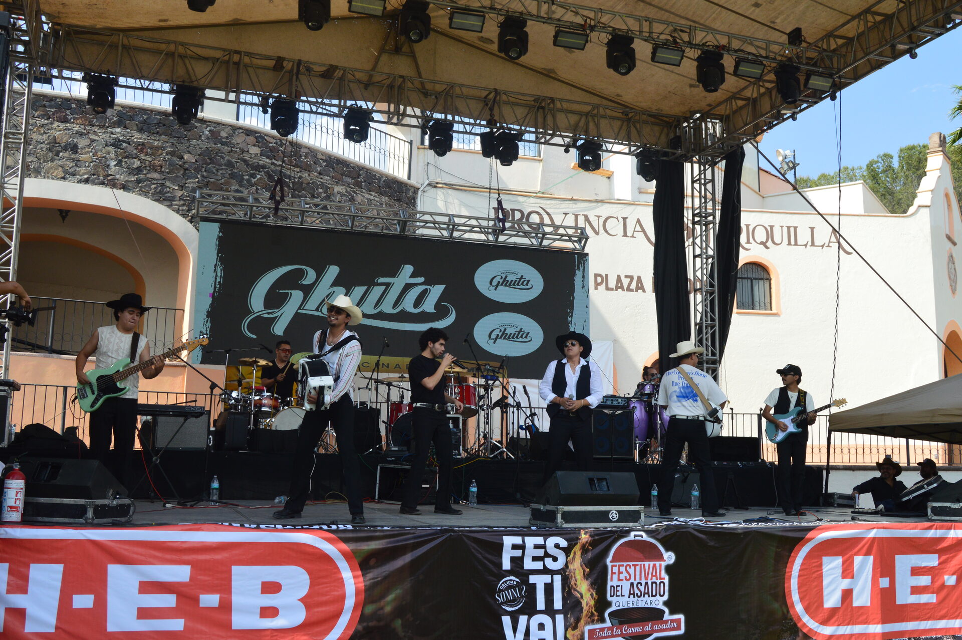 Banda norteña tocando en el escenario con banners HEB y Festival del Asado