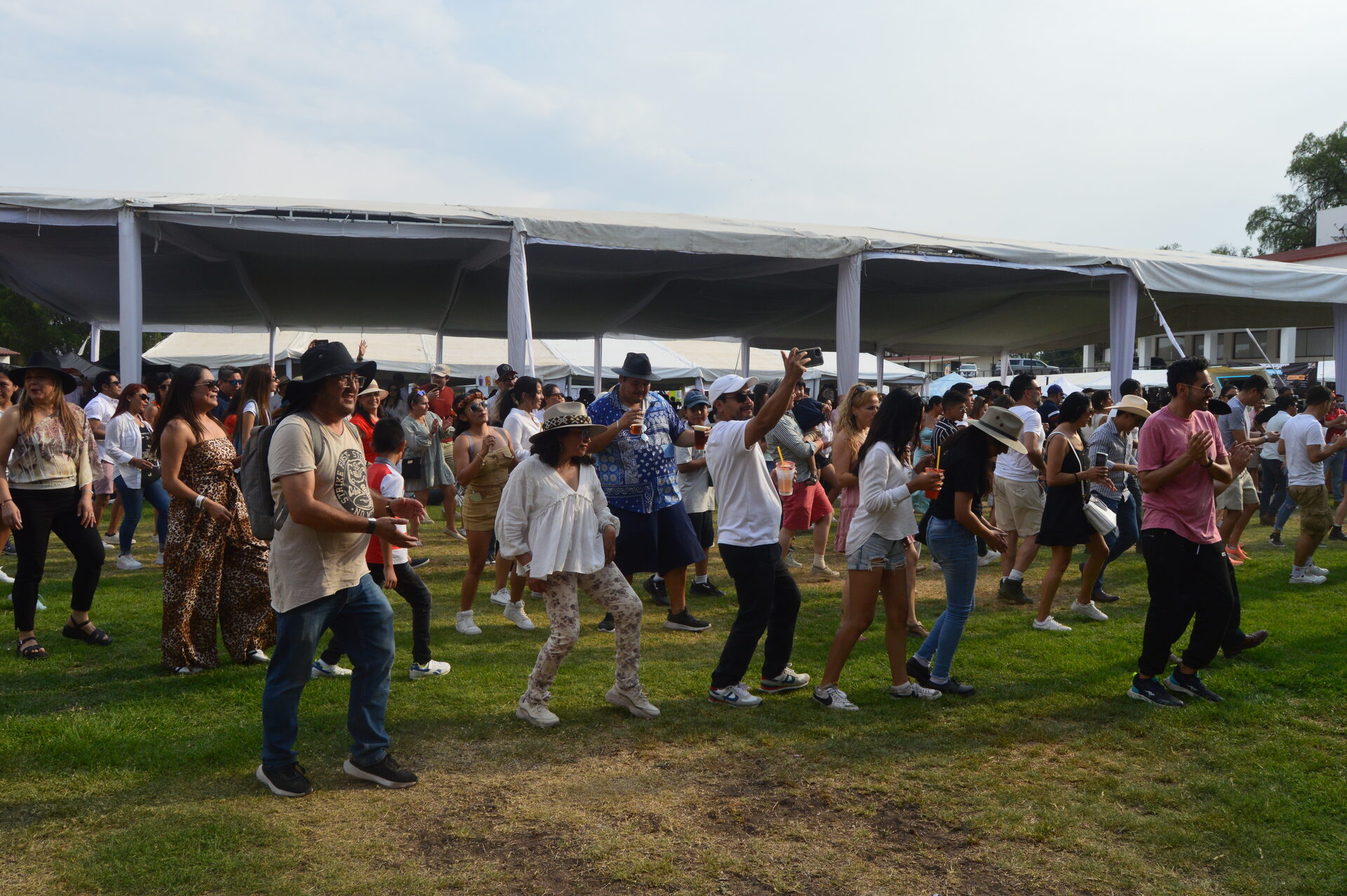 Público bailando y filmando frente al escenario con banners de patrocinadores